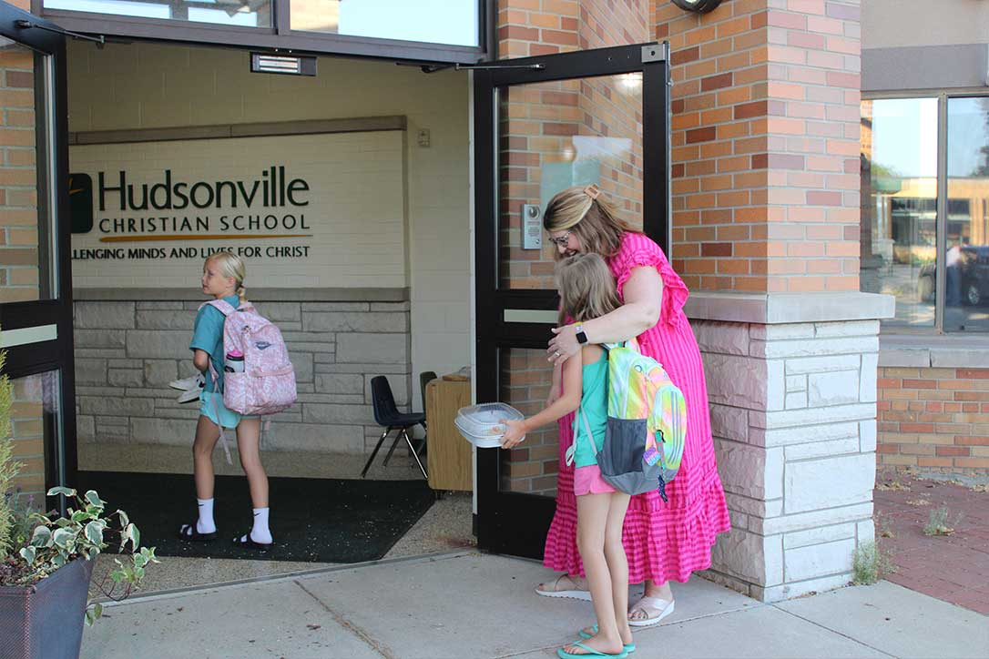 Elementary principal hugging student as she enters Hudsonville Christian School