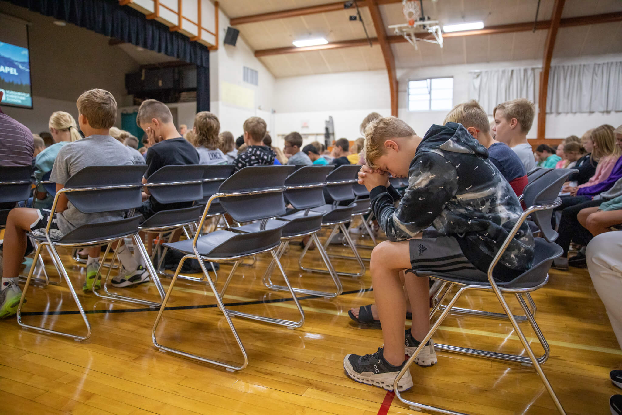 Middle school students praying at chapel in the gym at Hudsonville Christian School.