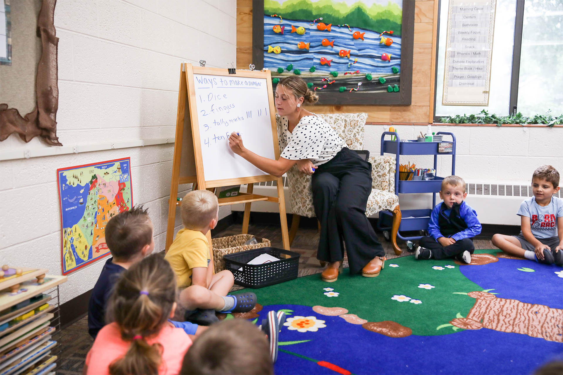 Teacher writing on a white board teaching students in a 4 School class at Hudsonville Christian Preschool.