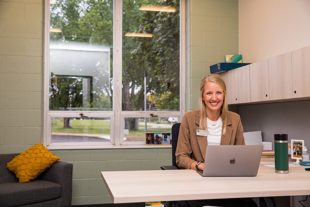 An admissions counselor smiles at her desk, ready to help students apply for Hudsonville Christian School enrollment.