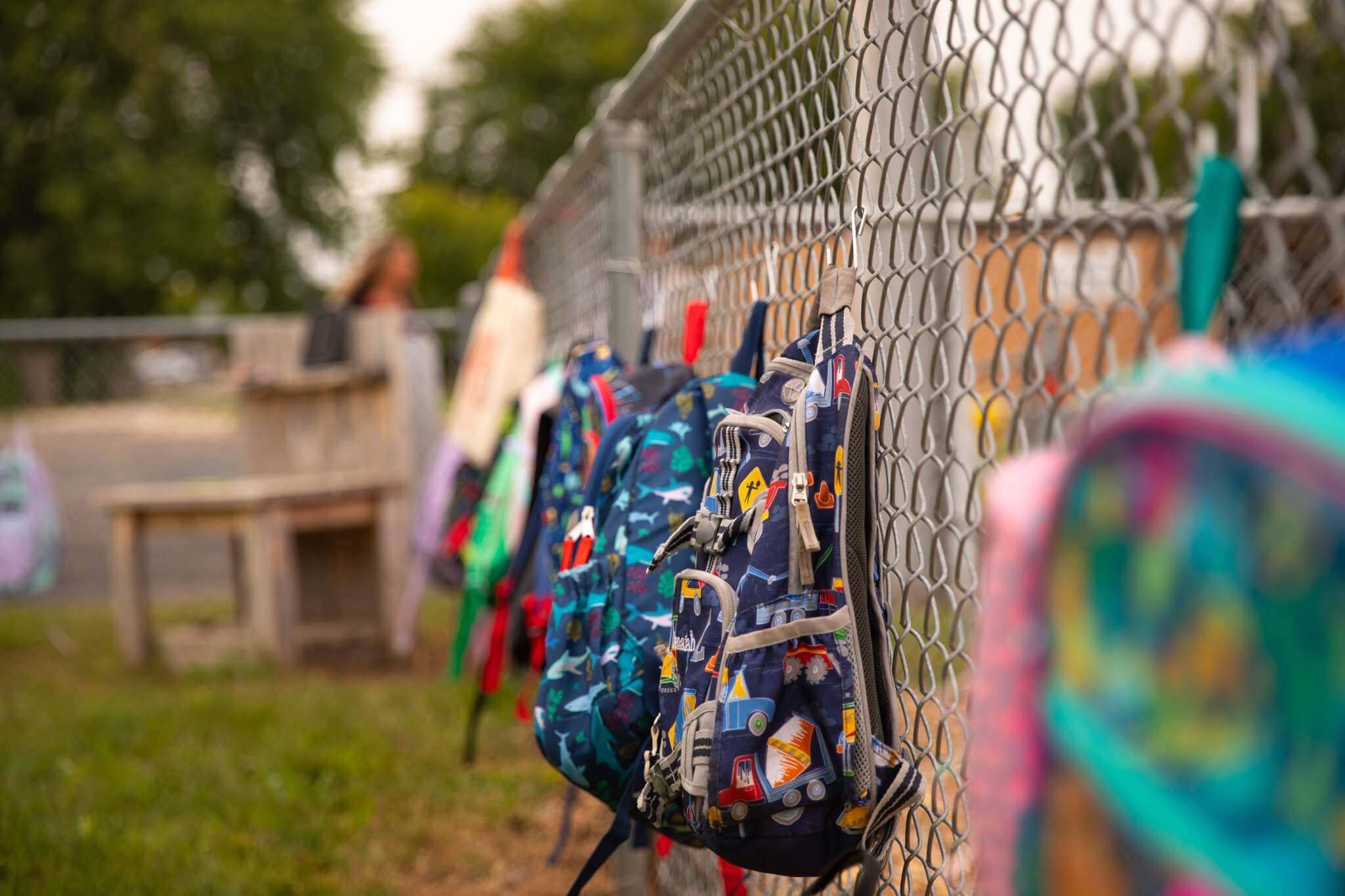 Backpacks hanging on a chain-linked fence at Hudsonville Christian School