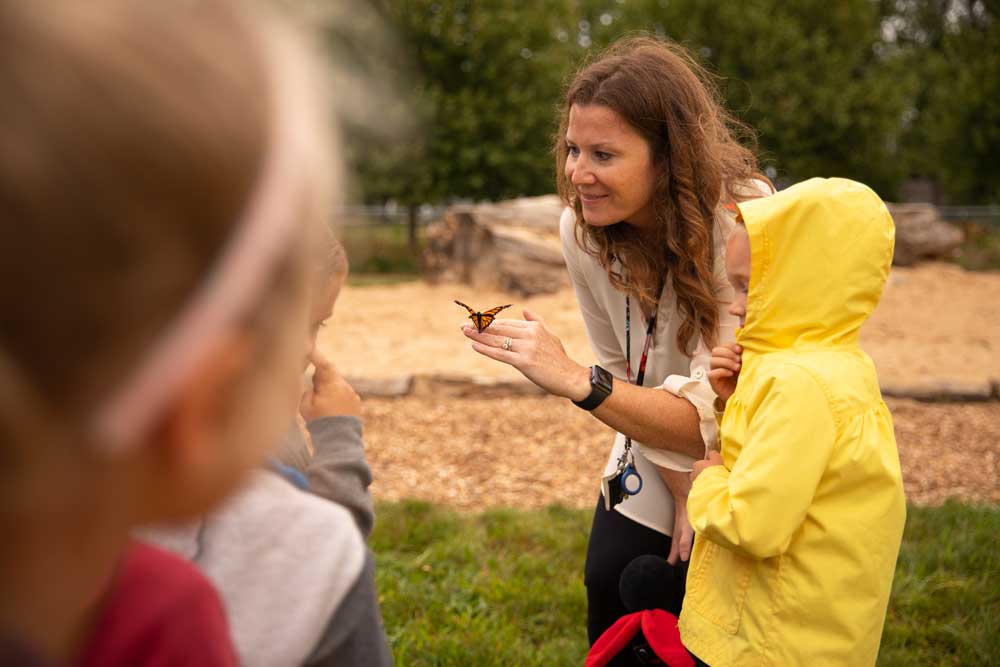 The teacher shows students a butterfly at Hudsonville Christian Preschool's Nature-Based 4 School.